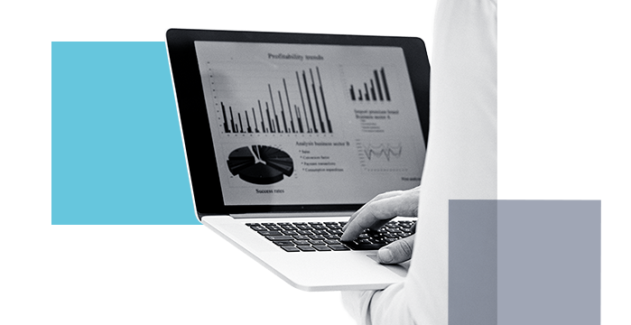 Someone typing on a laptop while looking over financial graphs and statistics